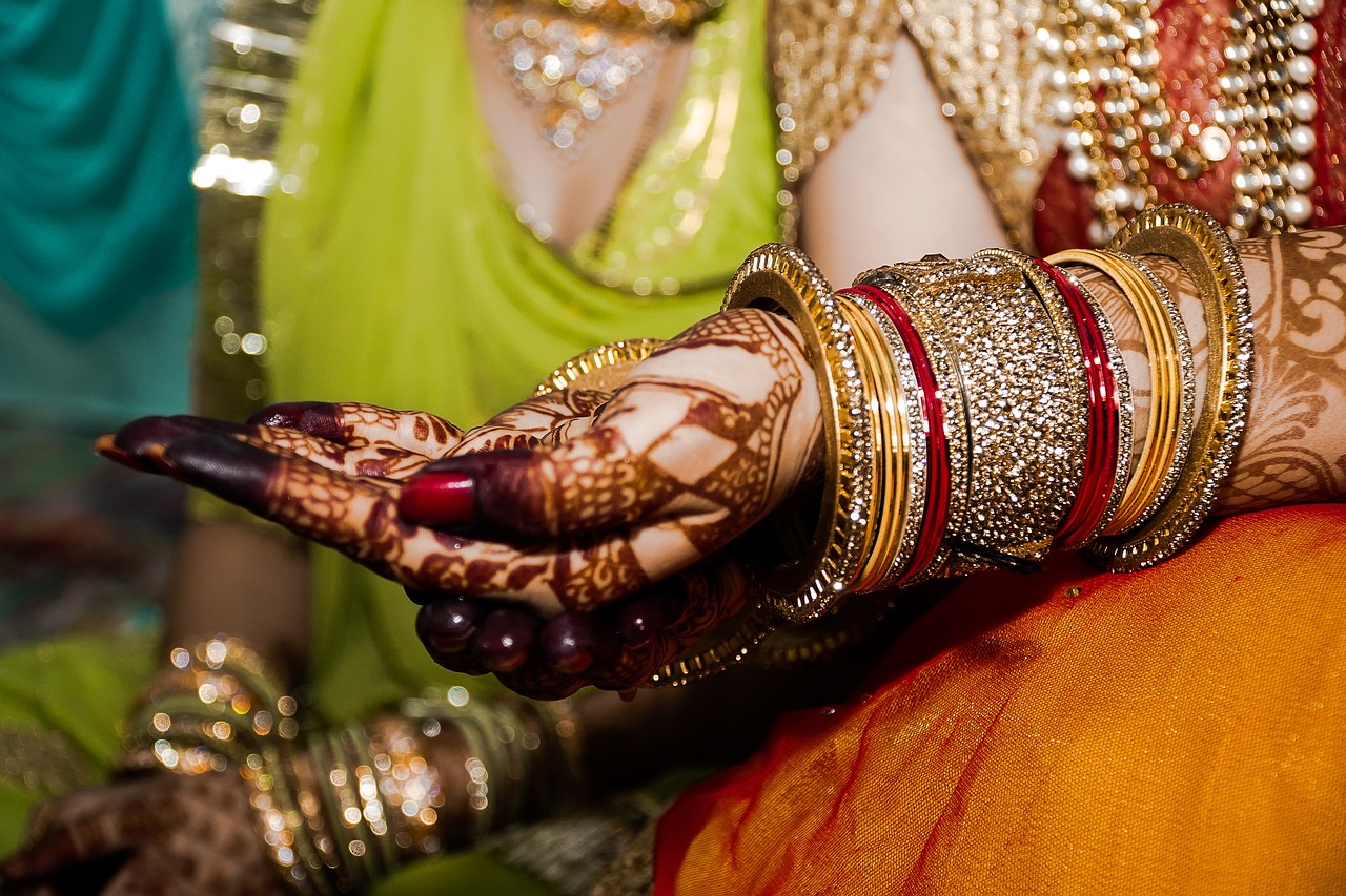 -up of a couple's hands clasped together in a traditional wedding pose, with a unique accessory such as a tribal necklace or a handmade flower crown